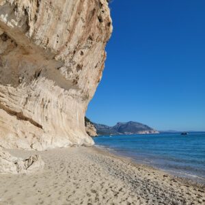 Big Cliff near the white sandy beach of Cala Luna with blue waters 
