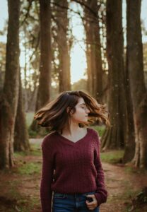 Girl turning head with hair flying in the air surrounded by trees